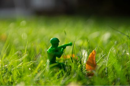 Small green toy soldier hiding in grass