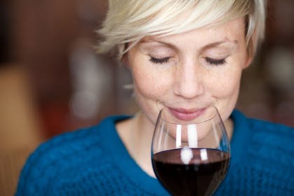 woman in blue jumper holding glass of red wine