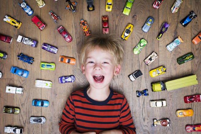 Boy lying on floor surrounded by toy cars