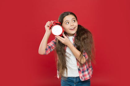 Girl holding clock to her ear