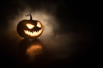 A scary carved pumpkin in a dark room