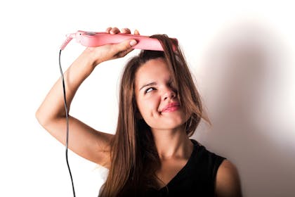 Woman curling hair with straighteners