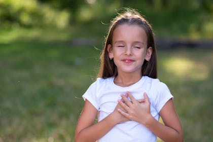 Girl with hands on heart standing outside