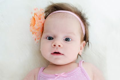 Baby with wide eyes wearing a flower headband