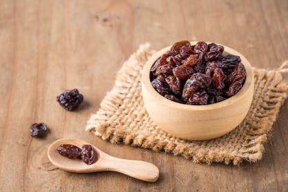 Wooden bowl of raisins with scoop