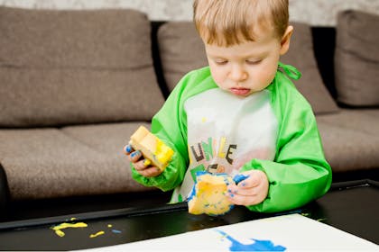 Little boy painting with sponges 