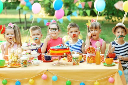 kids sitting round table at birthday party wearing fancy dress