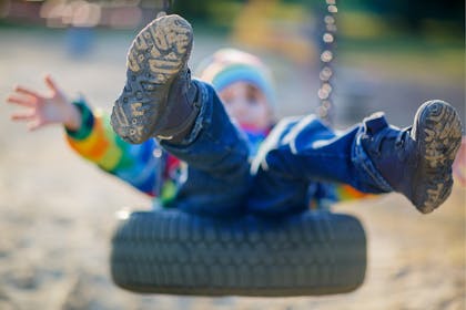 Child in wellies on a tyre swing