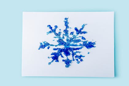 Blue painted snowflake picture with glued rock salt