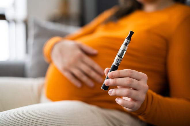 Pregnant woman holding vape