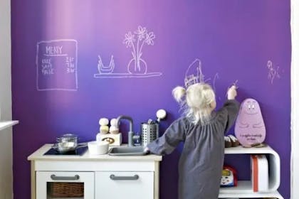 Little girl drawing on her bedroom wall with chalk