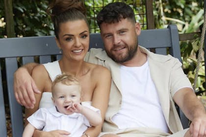 Danny Miller and wife and baby son cuddle on park bench