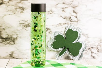 Sensory bottle play for toddlers with green glitter and shamrock sequins