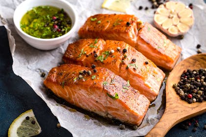 three cooked salmon steaks with peppercorns