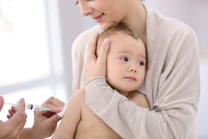 A baby being held by its mother as it receives a vaccination injection