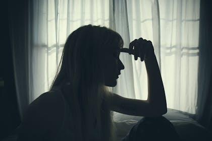 Silhouette of woman looking out of window