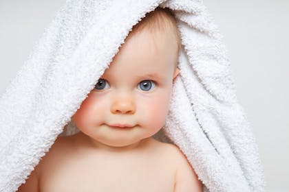 Baby biting lip with towel on head