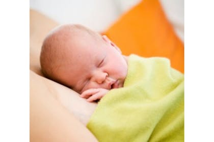 baby sleeping with green blanket over it