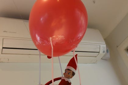 Elf on the Shelf arriving in Christmas gift bag carried by balloon 