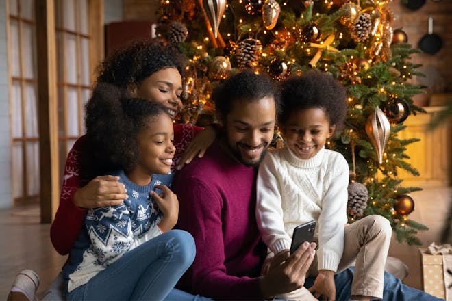 Family photo sat around the Christmas tree looking at phone