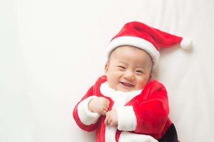 Baby smiling wearing Santa outfit