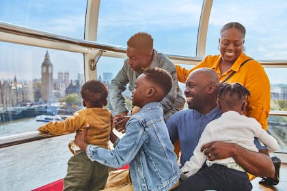 A smiling family enjoys views across London from their pod on the London Eye 