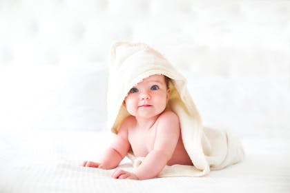 Baby wearing hooded blanket enjoying tummy time