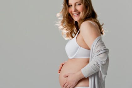 A pregnant woman in a bra holding her stomach