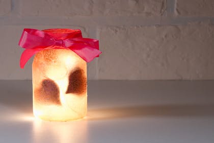 Glittery glass jar with heart silhouettes and candle inside