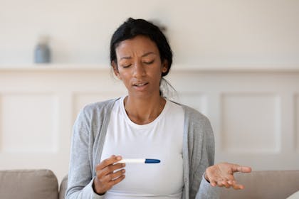 Confused woman holding pregnancy test