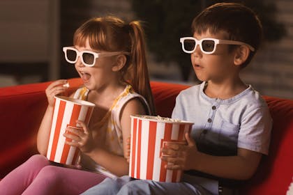 Two kids enjoying a movie night with popcorn
