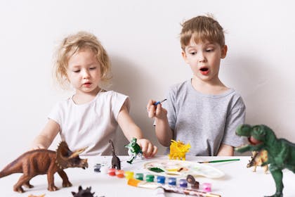 Boy and girl painting dinosaur figures
