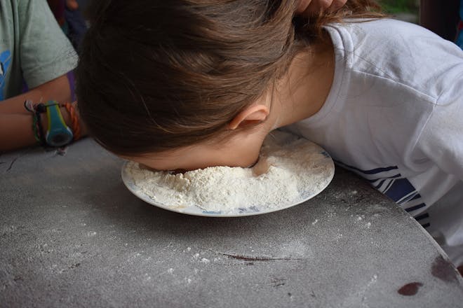 Girl with face in plate of flour as part of party game