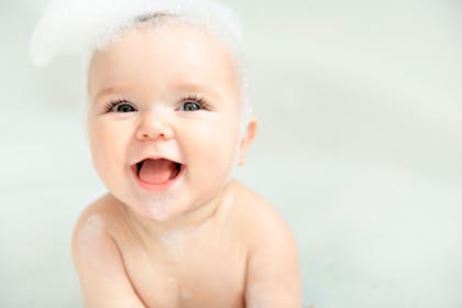 Laughing baby enjoying a bubble bath