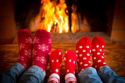 Family wearing cosy Christmas socks in front of the fire