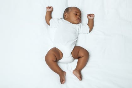 Baby fast asleep wearing white babygrow 