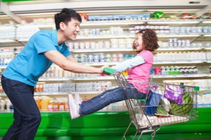man pushing girl in trolley in shop