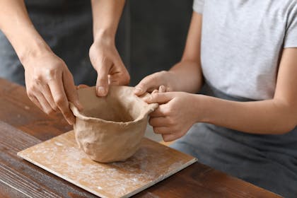 Child and parent making pinch clay ceramic pot craft