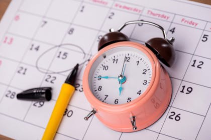 pink clock on calendar with pen marking date