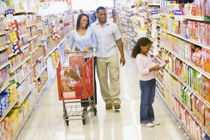 Family with shopping trolley walking down the food aisle in a supermarket.