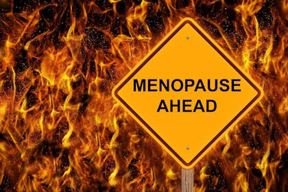 Menopause ahead sign against wall of fire