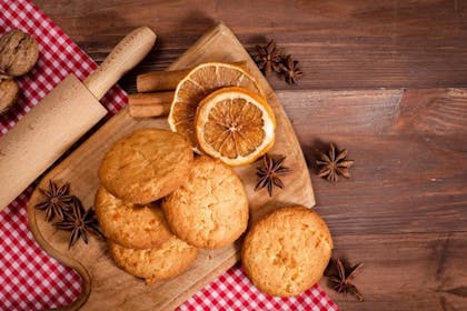 Shortbread biscuits next to dried orange slices and rolling pin