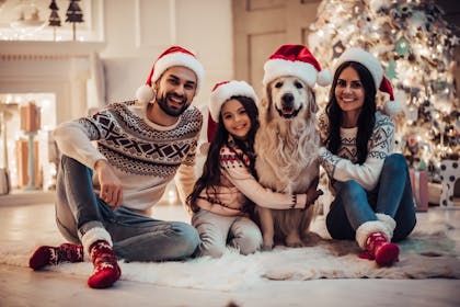 Christmas family photo wearing Santa hats with the dog