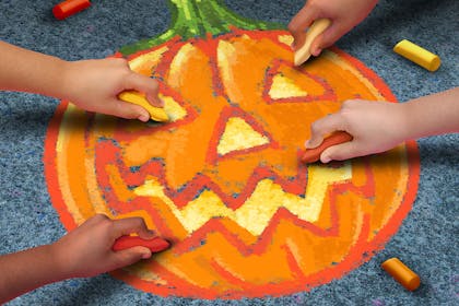 Kids drawing a pumpkin on pavement with chalk