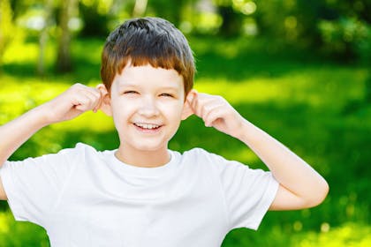 Boy holding ears to listen outdoors