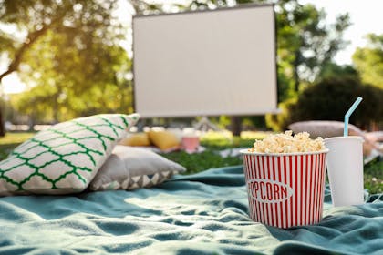 projector screen, cushions, blanket and popcorn in the garden