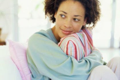 woman sitting on sofa hugging pillow