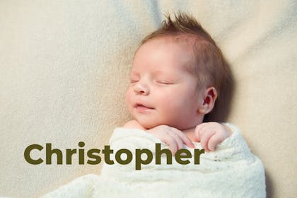 Sleeping baby wrapped in blanket and smiling. Name Christopher written in text