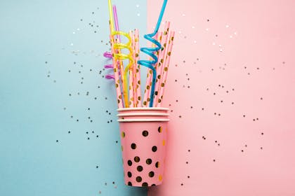 Pink sparkly paper party cup with pink and gold paper straws and blue and yellow twisty straws