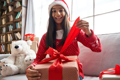 Teenage girl opening gift on Christmas day
